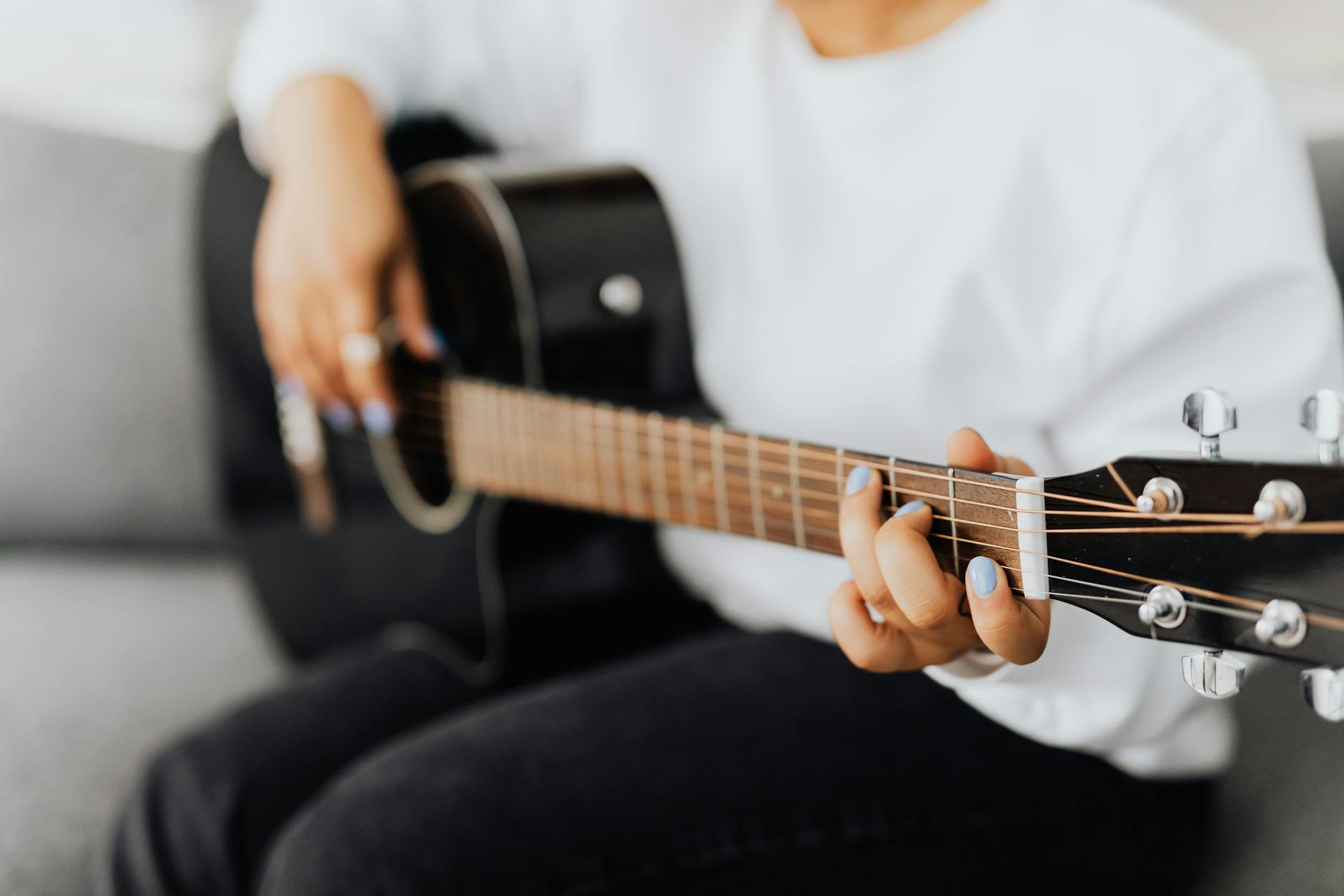 Dłoń początkującego gitarzysty na gryfie gitary akustycznej