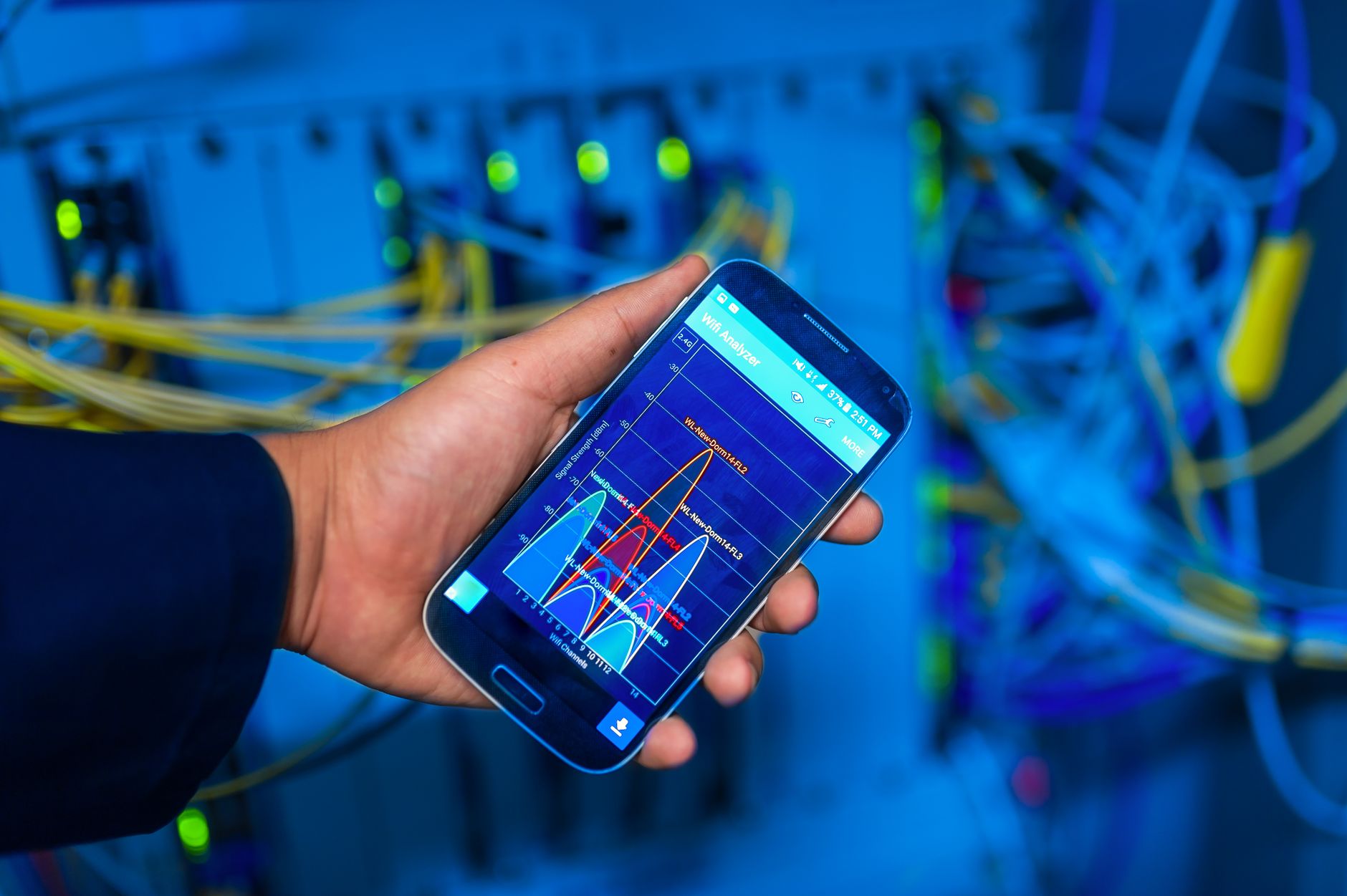 Dłoń z smartfonem pokazującym analizę sieci na tle serwerowni
