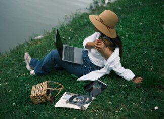 Kobieta odpoczywa nad rzeką z laptopem i tabletem w letni dzień