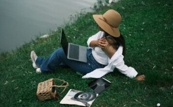 Kobieta odpoczywa nad rzeką z laptopem i tabletem w letni dzień