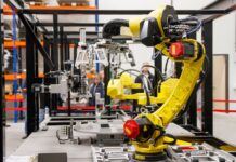 Żółte ramię robota przemysłowego pracujące w nowoczesnej fabryce samochodów