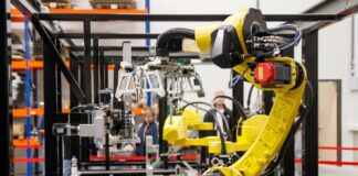 Żółte ramię robota przemysłowego pracujące w nowoczesnej fabryce samochodów