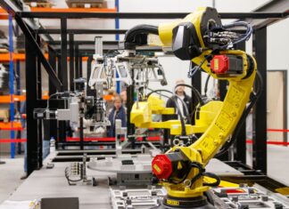 Jak sztuczna inteligencja zmienia fabryki samochodów w inteligentne zakłady Żółte ramię robota przemysłowego pracujące w nowoczesnej fabryce samochodów