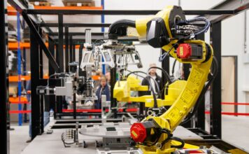 Jak sztuczna inteligencja zmienia fabryki samochodów w inteligentne zakłady Żółte ramię robota przemysłowego pracujące w nowoczesnej fabryce samochodów