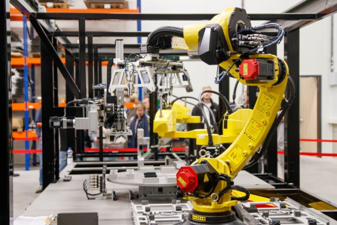 Żółte ramię robota przemysłowego pracujące w nowoczesnej fabryce samochodów Żółte ramię robota przemysłowego pracujące w nowoczesnej fabryce samochodów