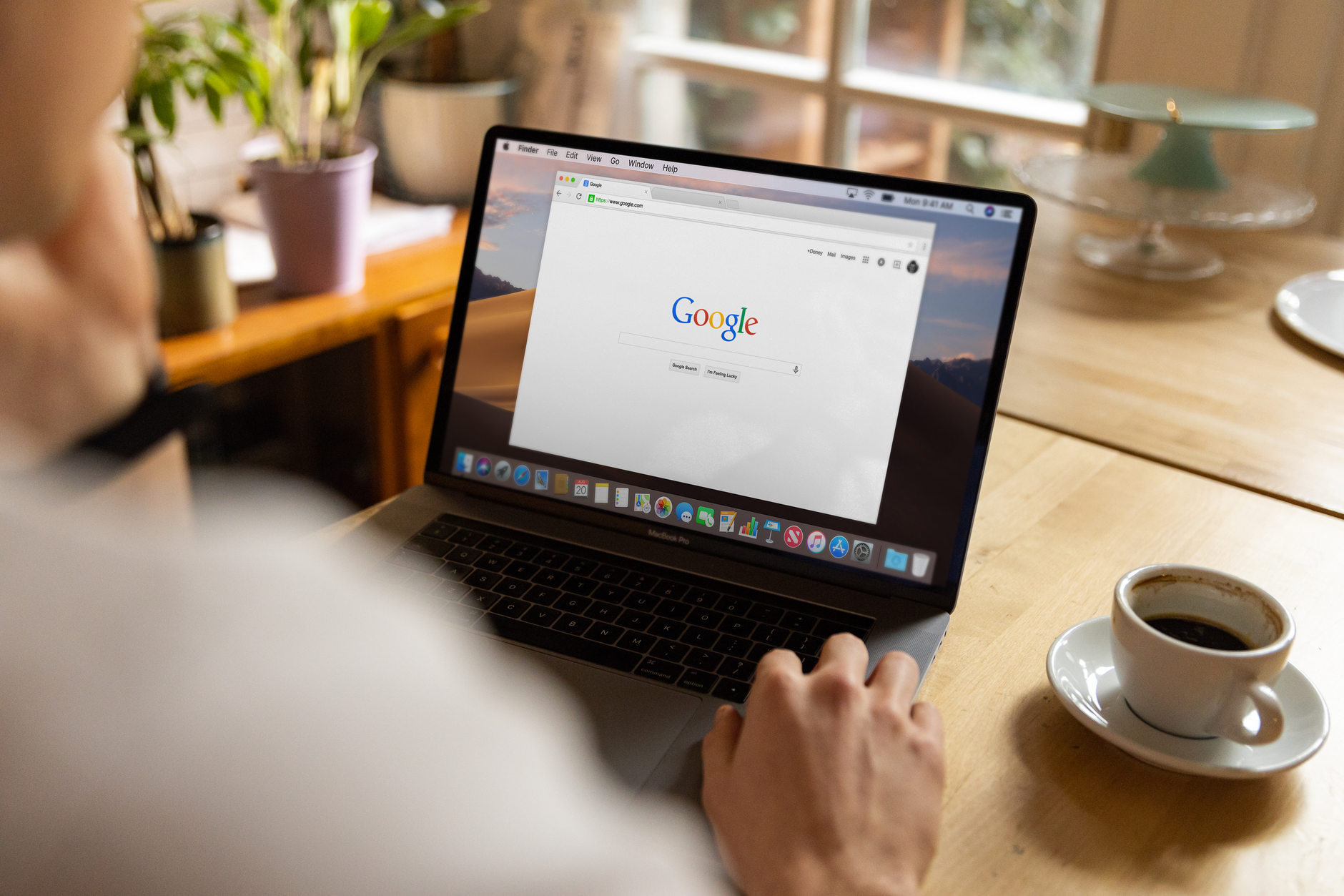 Dorosła osoba przegląda Google na laptopie przy drewnianym stole z kawą