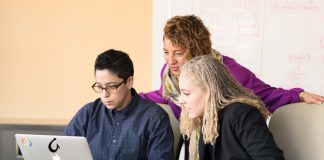Trzy osoby współpracują przy laptopie w biurze nad procesem CI/CD