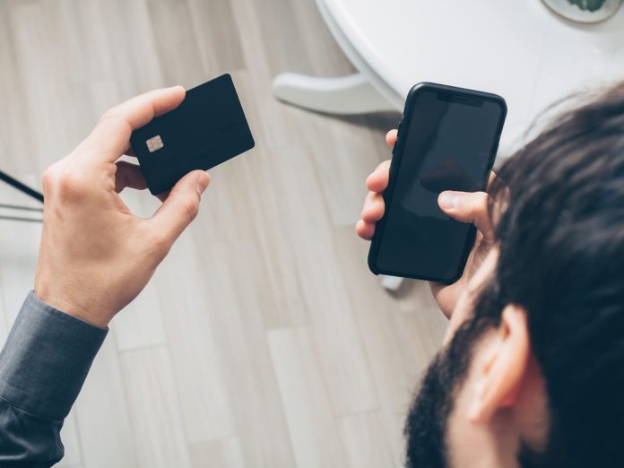 Mężczyzna płaci online smartfonem i kartą kredytową Mężczyzna płaci online smartfonem i kartą kredytową